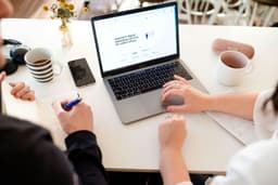 Two people talking over a laptop